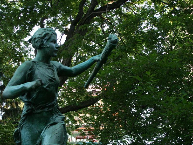 image of greek games statue in front of green bushes